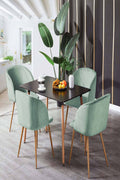 Sienna dining table with green upholstered chairs beside a tall indoor plant.