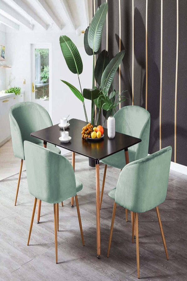 Sienna dining table with green upholstered chairs beside a tall indoor plant.