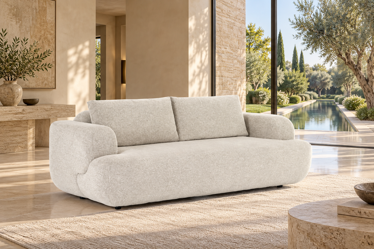 AI-assisted villa-style visual reference of the pale-toned Herman sofa with two broad back cushions, rounded block arms and small dark supports, inside a tall glazed stone villa overlooking a garden pool. Styling accessories are not confirmed inclusions.