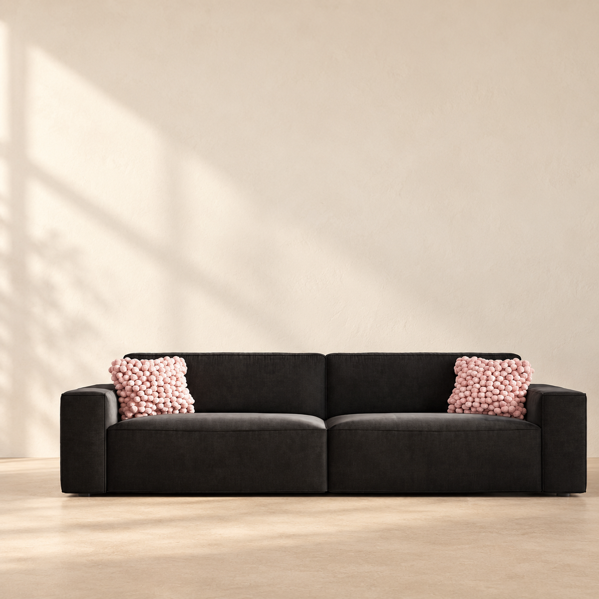 AI-assisted styled view of the Jessie sofa, showing its dark upholstery, broad arms and two pink cushions.
