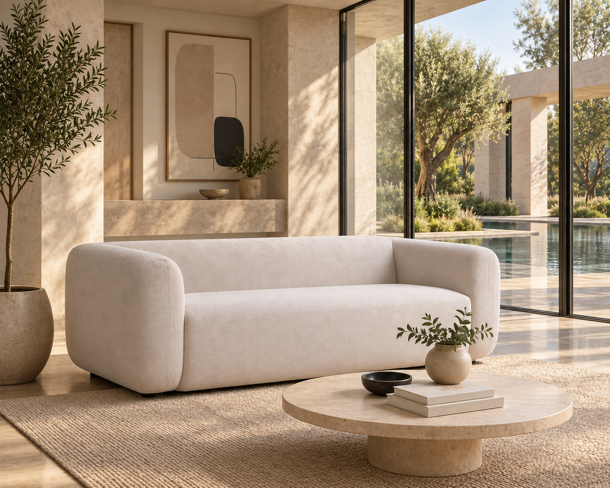 AI-assisted villa-style visual reference of the cream-toned Nara sofa with its continuous back and bench seat beside tall glazing and a garden pool. Foreground table and plant are styling, not confirmed inclusions.